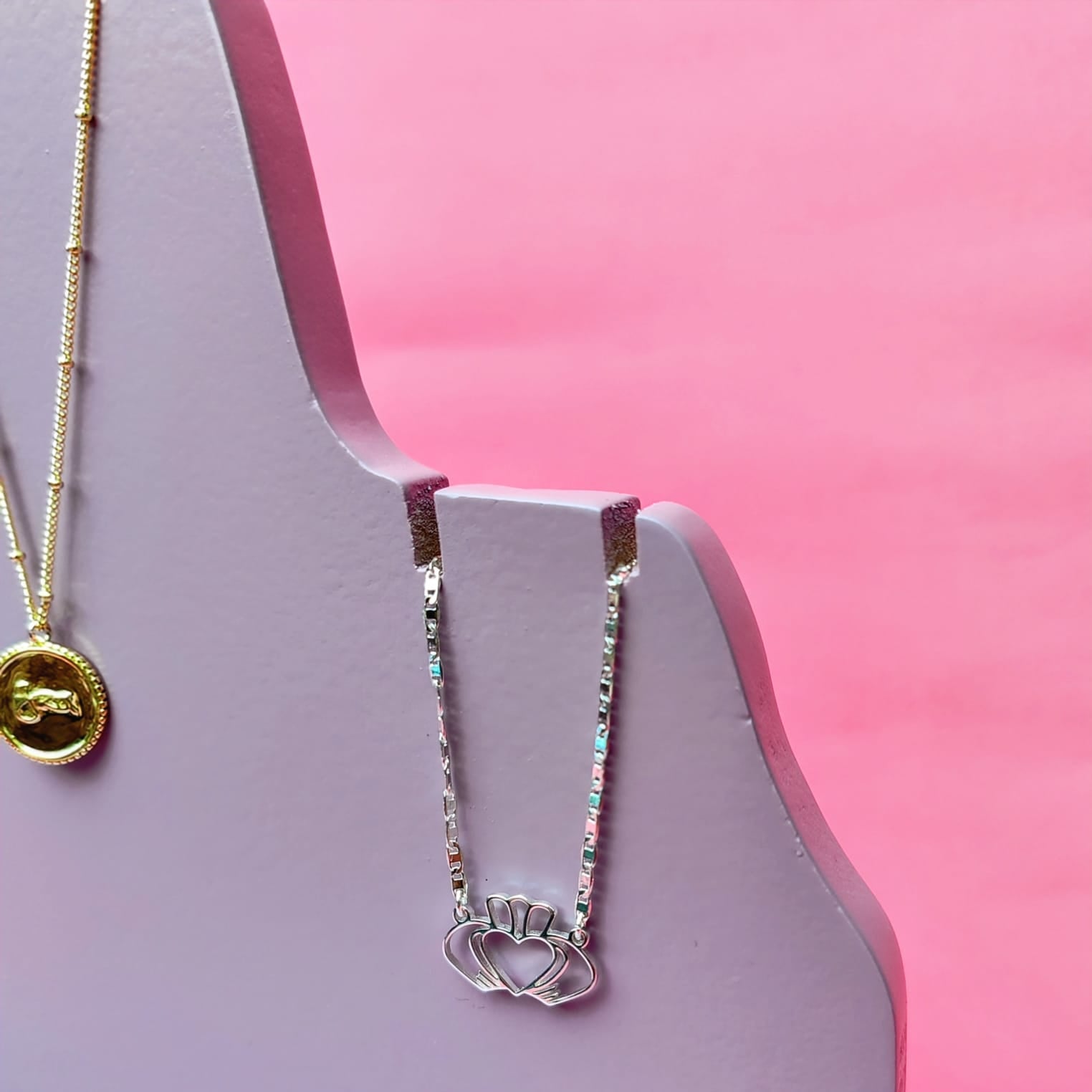 Display of gold Grá medallion necklace and silver claddagh necklace