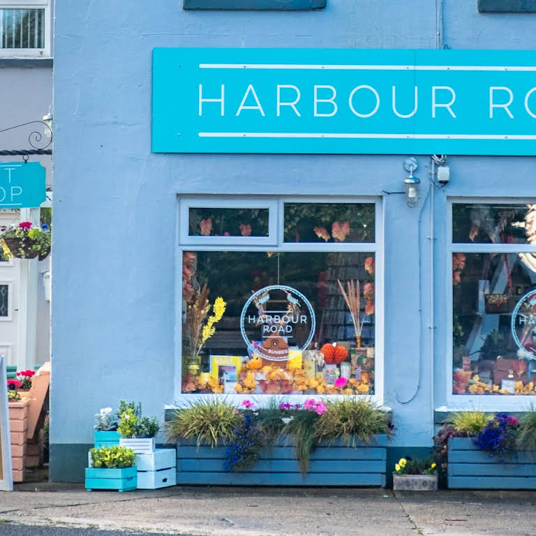 Harbour Road shopfront in blue with a circular Harbour Road sign, window displays and flower planters