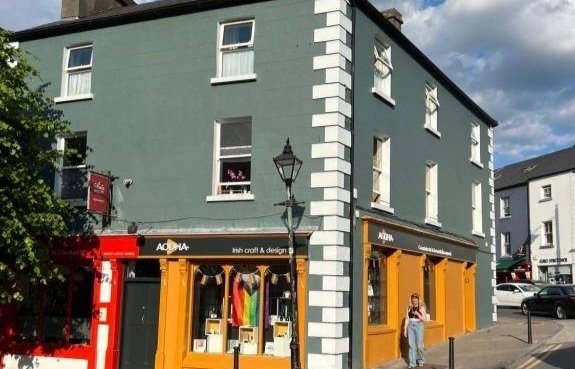 Street scene with a row of shops in orange awnings and a green building with white window frames