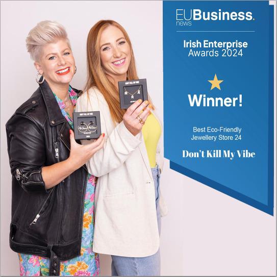 Two women holding a trophy plaque beside an EUBusiness news award poster reading Winner